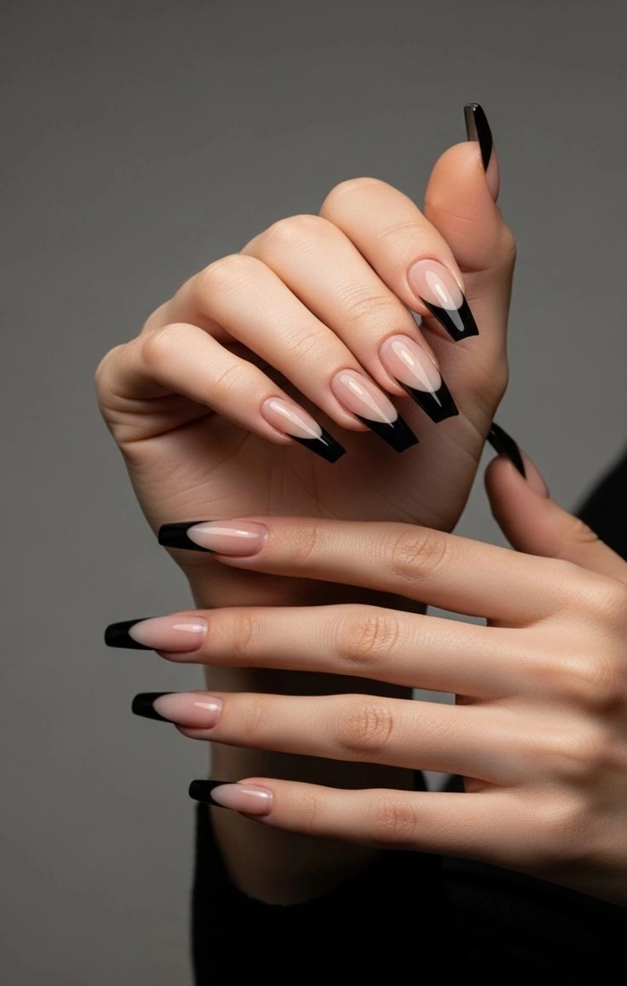 Glossy black French tip nails on a neutral nude base Glossy black French tip nails on a neutral nude base