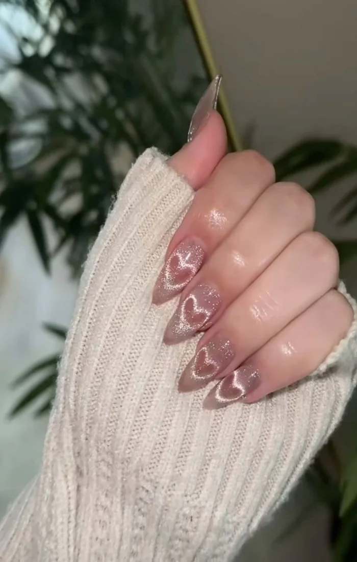 Pink cat eye nails with a small red heart accent. Pink cat eye nails with a small red heart accent.